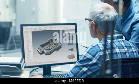 Two Senior Engineers Working With Detail Blueprint on a Personal Computer. They Actively Discuss Various Plans and Schemes. Stock Photo
