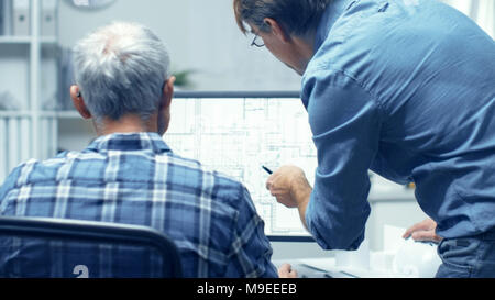 Two Senior Architectural Engineers Working With Building Plan on a Personal Computer. They Actively Discuss Various Plans and Schemes. Stock Photo