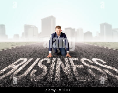 Young determined businessman kneeling before business text  Stock Photo
