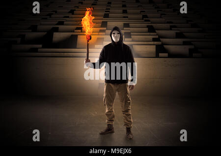 Ugly, aberrant man coming out from the labyrinth with burning flambeau on his hand  Stock Photo