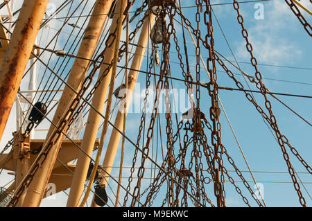 Rusty chains hanging from the mast of a large fishing trawler boat. Stock Photo