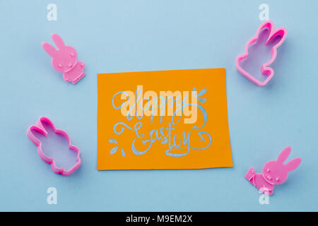 Silicone molds and Easter greeting card. Four rabbit shaped silicone molds and yellow Easter greeting card. Easter holidays handmade composition. Stock Photo