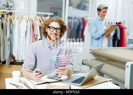 Portrait of smiling businessman working with patterns with designer in the background Stock Photo