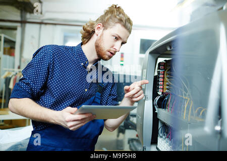 Young operator examining printing machine on factory Stock Photo