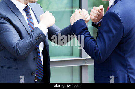 two businessmen standing outside and fighting with their fists Stock Photo