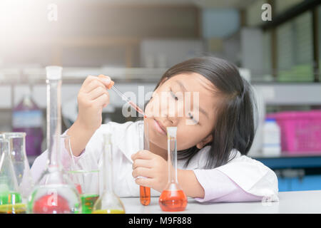 little girl in lab coat making experiment with test tube in chemical laboratory, science and education concept Stock Photo