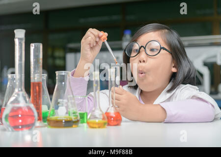 Excited little girl in lab coat making experiment with test tube in chemical laboratory, science and education concept Stock Photo
