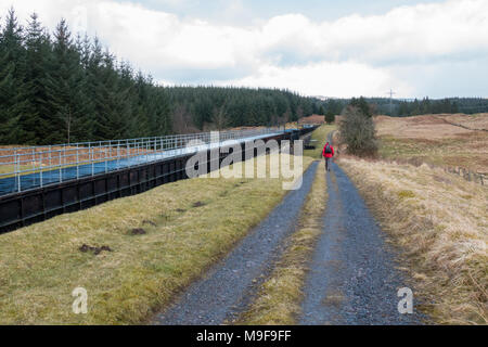 walker on Rob Roy Way between Drymen and Aberfoyle walking past the Corrie Aqueduct, part of the Loch Katrine pipeline that supplies water to Glasgow Stock Photo