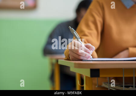 Students taking exam in classroom. Education test and literacy concept. Cropped shot, hand detail. Stock Photo