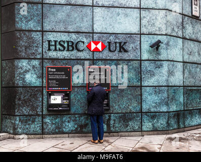 Rear view of a man withdrawing money from a HSBC Bank ATM, Queen Victoria Street, London, EC2, England, UK. Stock Photo