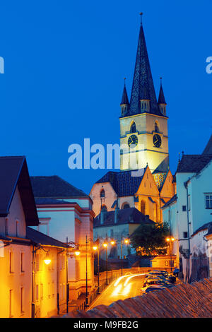 View of Sibiu streets on background with tower of cathedral in night lights, Romania Stock Photo