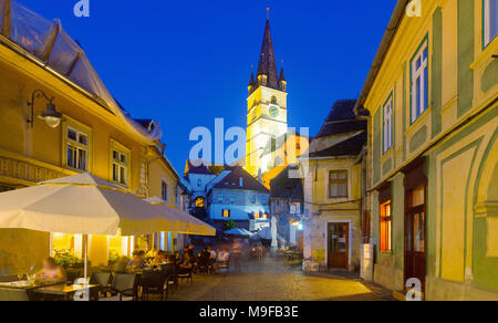 View of Sibiu streets on background with tower of cathedral in night lights, Romania Stock Photo