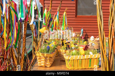 Traditional souvenirs displayed on the table during Easter street market. Wooden baskets with young green cereal sprouts, easter eggs, figures of East Stock Photo