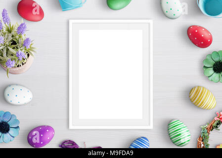 Blank picture frame surrounded with easter eggs and flowers. Stock Photo