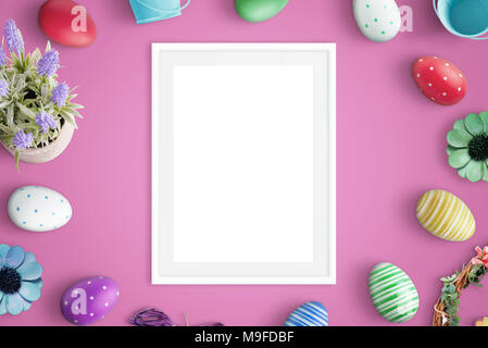 Picure frame mockup on pink desk. Easter decorations beside. Flat lay. Stock Photo