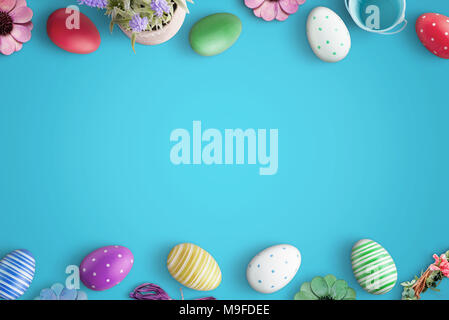 Easter eggs and flowers on blue surface. Flat lay, top view scene with free space for text. Stock Photo