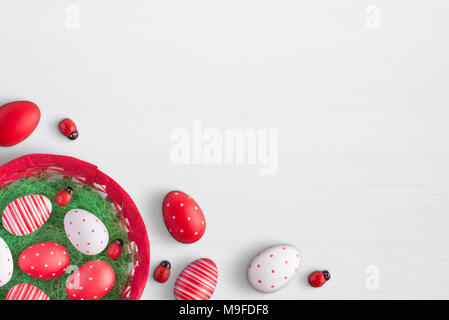 Easter basket with eggs and ladybug decorations. Free space for text on white wooden surface. Stock Photo