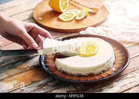 sweet cake with lemon on the table, cut a piece in the hands of the girl Stock Photo