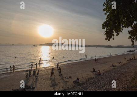 People playing at sunset on tropical beach in Ao Nang Stock Photo