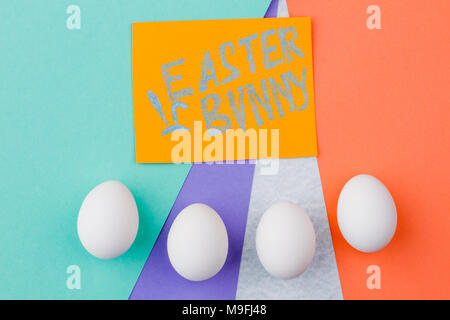 Easter eggs and text Easter bunny. White eggs on colorful background. Easter symbols and traditions. Stock Photo