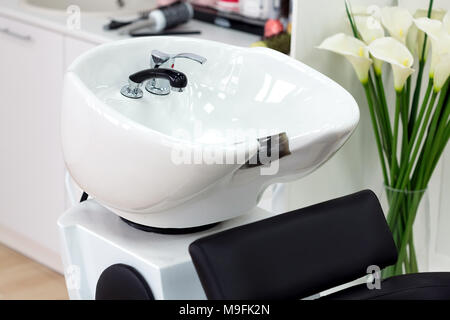 Closeup shot of chair with bowl for hair washing in hairdresser salon. Main focus is on the faucet Stock Photo