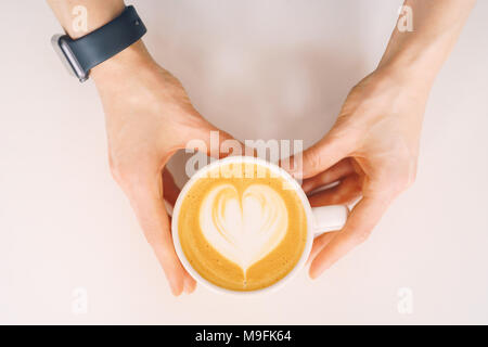 top view of the hand with a cup of coffee (cappuccino) in white background Stock Photo