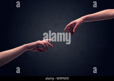 Two male hands reaching out to one another, almost touching, in front of dark clear empty background wall concept Stock Photo