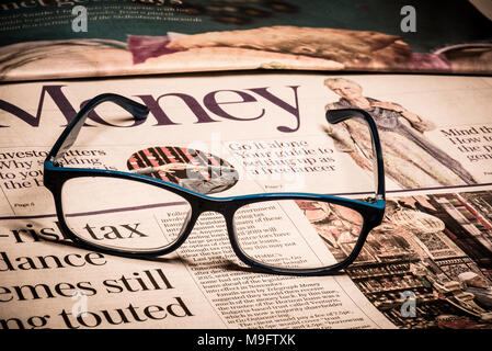 Reading glasses placed on financial newspaper Stock Photo