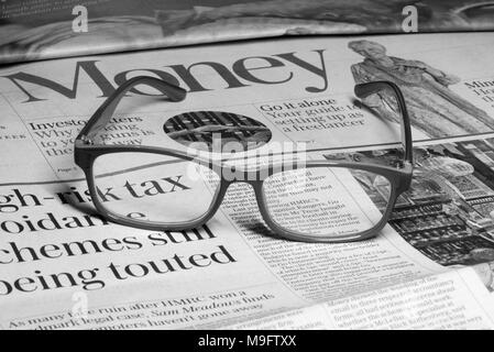 Reading glasses placed on financial newspaper Stock Photo