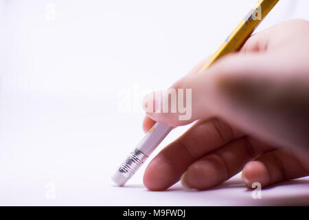 A woman's hand is erasing something with the rubber sticking with the pencil on the white background. There are the plain background on the left side  Stock Photo