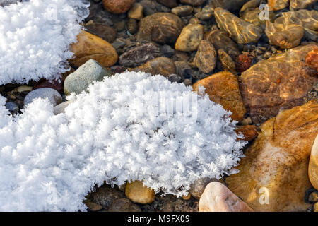 42,748.08650 close-up, soft white snow and feather-like ice crystals rest quietly on cold winter reddish red river rocks Stock Photo