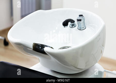 Closeup shot of chair with bowl for hair washing in hairdresser salon. Main focus is on the faucet Stock Photo