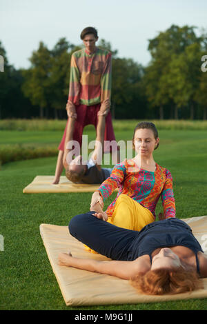 Thai yoga practise at the summer outdoor. Mats on the park lawn surface. Stock Photo