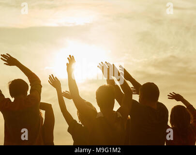 Silhouettes of happy people with hands up. Warming-up before sport exercises. Stock Photo