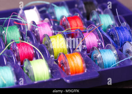 colored bobbins for sewing in a violet plastic box Stock Photo