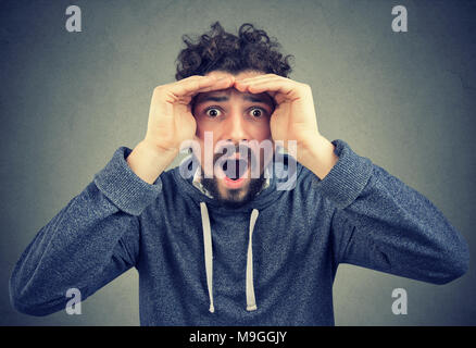 Shocked bearded guy looking forward with hands around face and looking stunned with forecast. Stock Photo