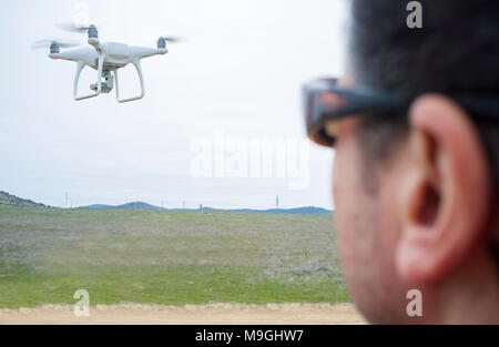 Pilot flying drone a cloudy day on countryside. Approaching maneuver Stock Photo