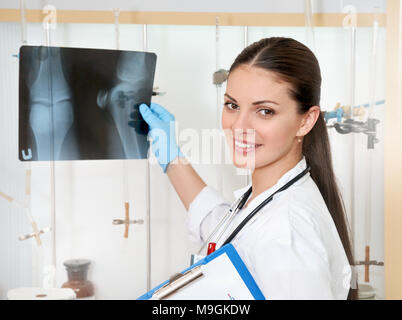 Medical concept of young beautiful female doctor in white coat with roentgen in hand. Woman hospital worker looking at roentgen and smiling Stock Photo