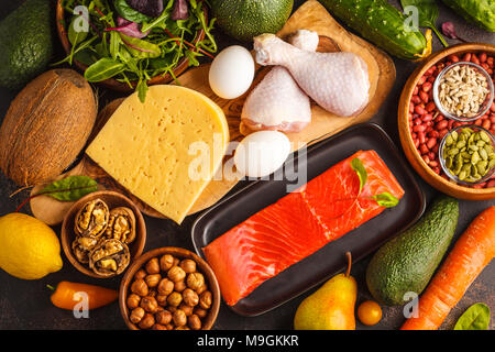 Keto diet concept. Balanced low-carb food background. Vegetables, fish, meat, cheese, nuts on a dark background. Stock Photo