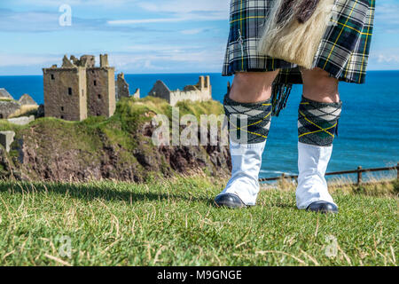 Traditional scottish bagpiper in full dress code at Dunnottar Castle in Stonehaven Stock Photo