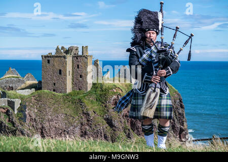 Traditional scottish bagpiper in full dress code at Dunnottar Castle in Stonehaven Stock Photo