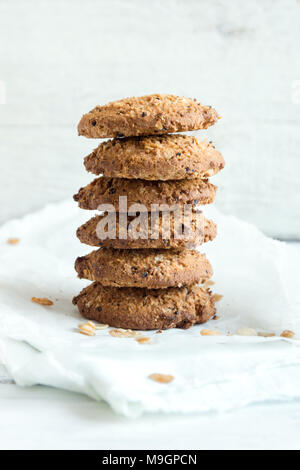 Homemade wholegrain cookies with oatmeal, lin and sesame seeds on white wooden table, copy space. Healthy vegan wholegrain cookies. Stock Photo