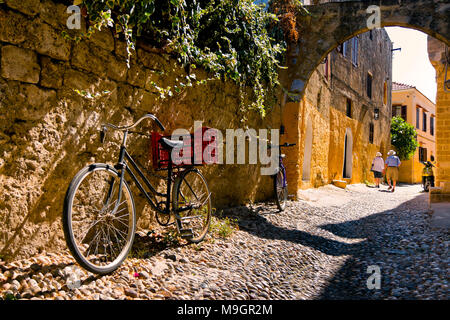 RHODES, GREECE - SEPTEMBER 30: Tourists admire charming secret narrow streets of Rhodes Island, bicycles in the foreground. September 30 2011, Greece Stock Photo