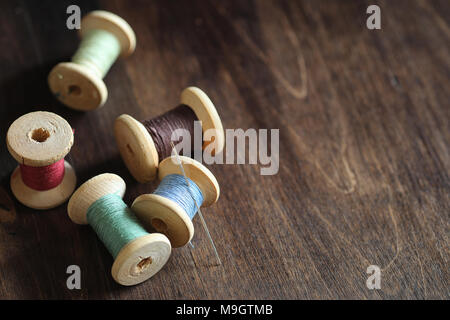 Sewing thread on a wooden background. Set of threads on bobbins  Stock Photo