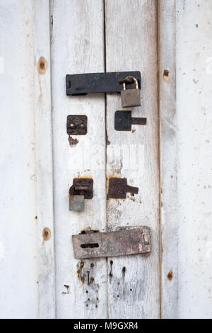 White door with an old lock with traces of previous locks on it Stock Photo