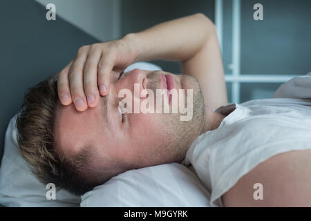 man lying in bed at home suffering from headache or hangover Stock Photo