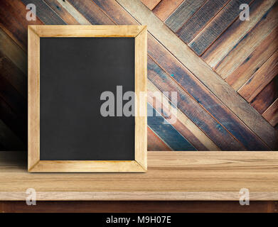 Blackboard on plank wooden table top at diagonal tropical wood wall,Template mock up for adding your design and leave space beside frame for adding mo Stock Photo