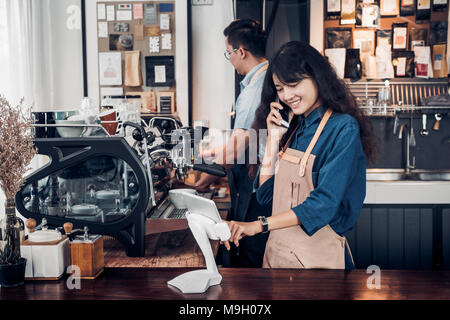 Asia Barista waiter use tablet take order from customer in coffee shop,cafe owner writing drink order at counter bar,Food and drink business concept,S Stock Photo