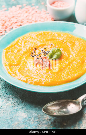 Red lentil soup in blue plate over blue stone backgroud