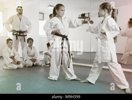 Young girls practicing in pair to use new techniques during karate class Stock Photo